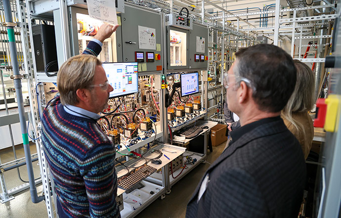 Three people in a lab look at research equipment.