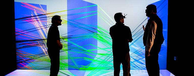 Photo of three people viewing a large-scale 3D visualization