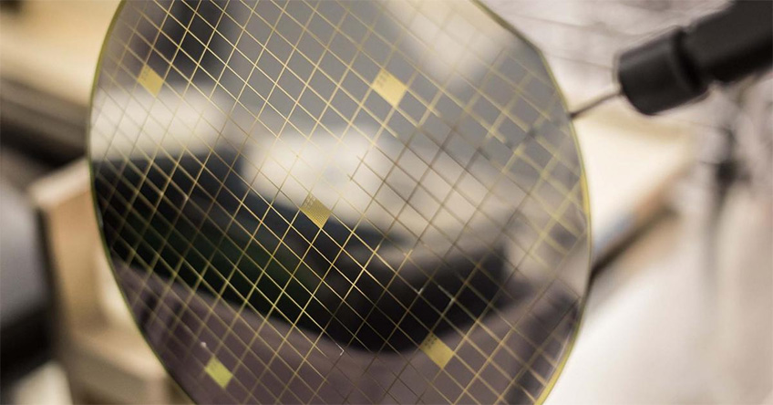 A translucent silicon wafer is at the foreground with a blurred background.