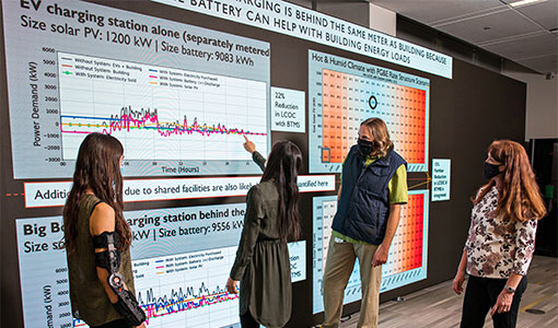 Four researchers review data on a large screen.