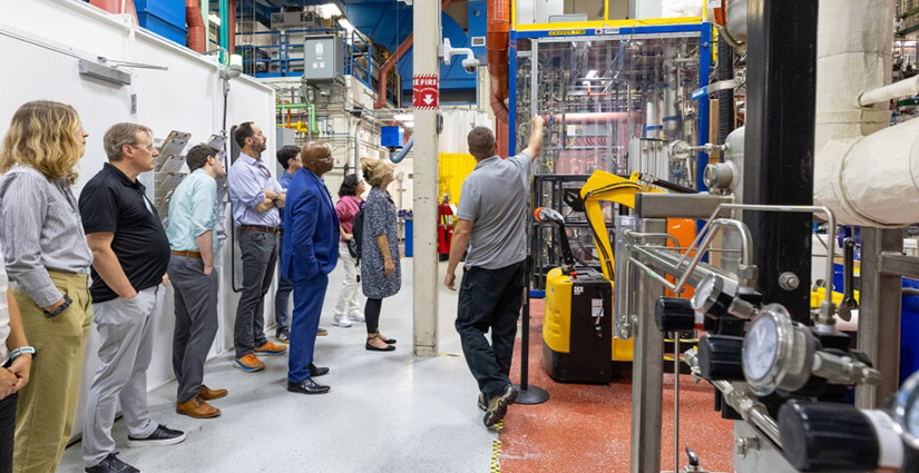 A group of people inside a laboratory look at objects pointed out by another person.