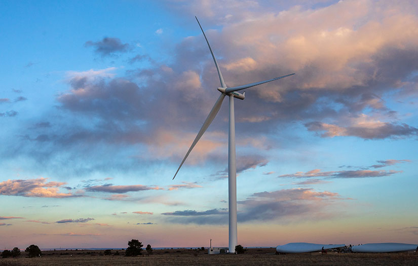 Wind turbine stands tall in a field at dusk