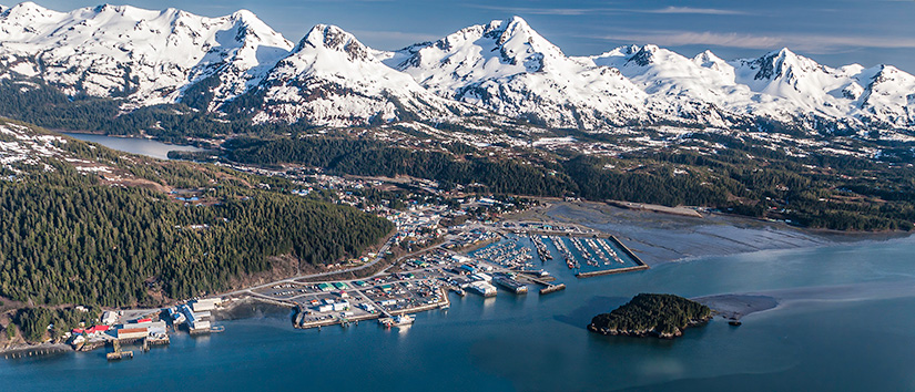 Aerial view of Cordova, Alaska shoreline with mountain range in background.