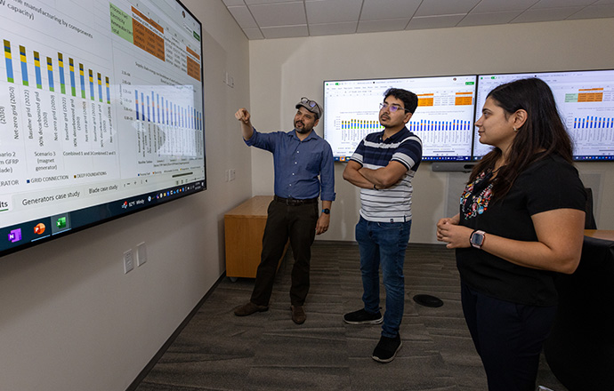 Three researchers looking at data on a large screen.