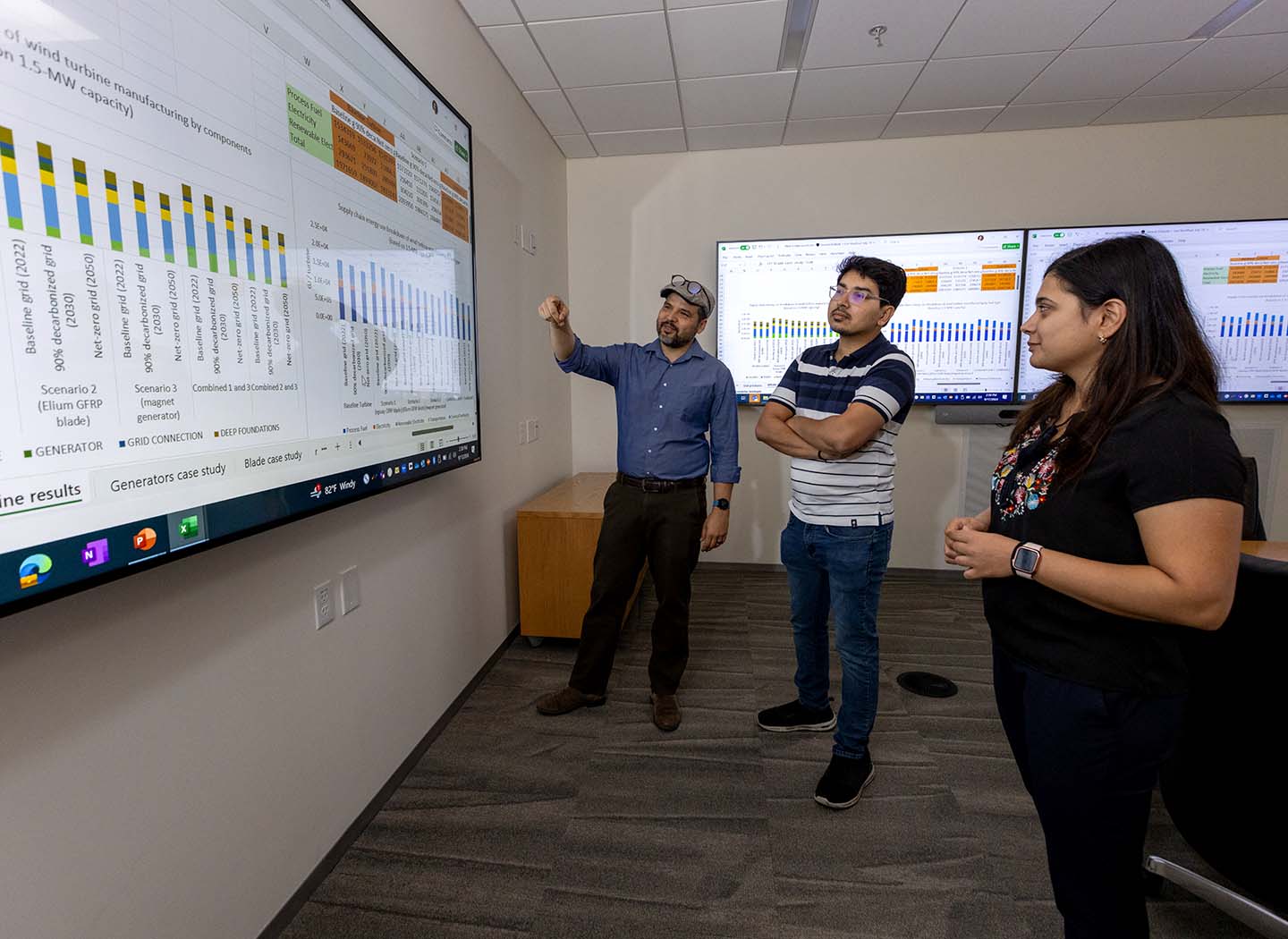 Three researchers looking at data on a large screen.