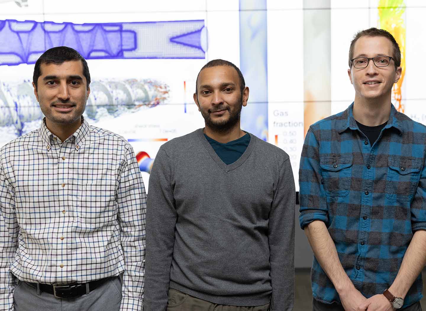 Three people standing in front of a data visualization