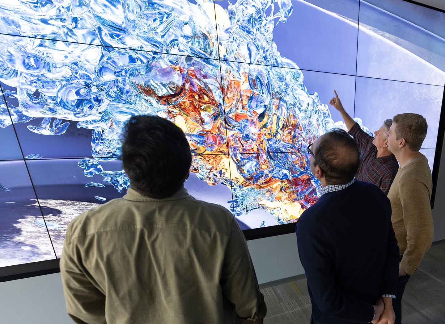 Four people stand in front of a large screen showing a detailed simulation of sustainable aviation fuel as it combusts in a virtual jet engine.