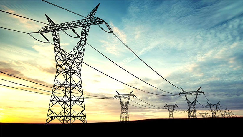 Transmission lines in a field at dawn