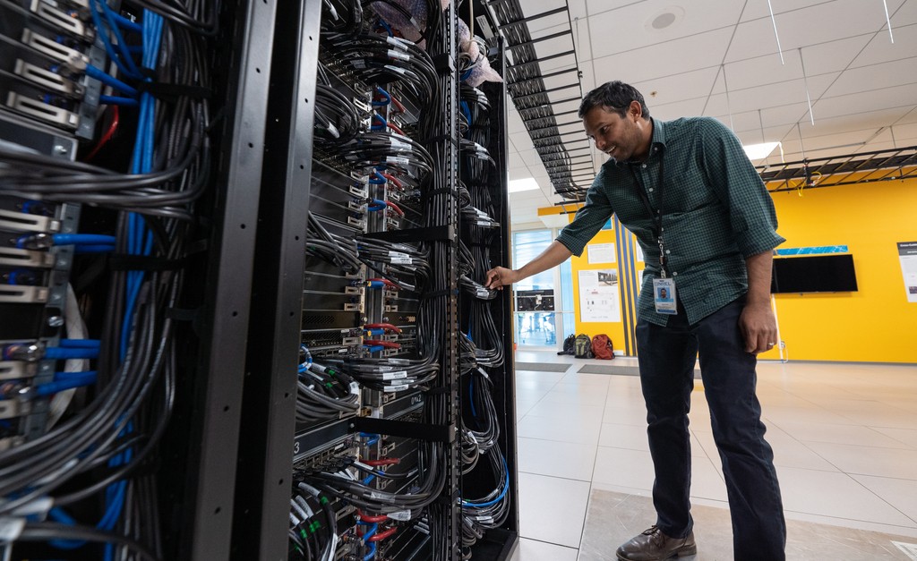 Photo of a person bent over adjusting a supercomputer