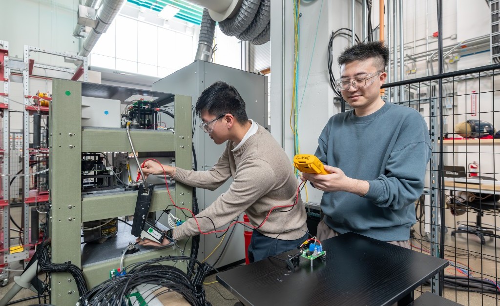 Photo of two people testing a medium-voltage test bed inside a laboratory