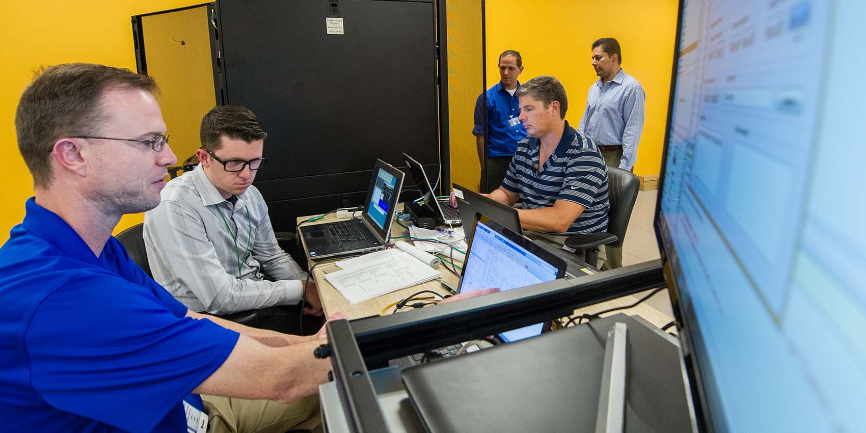 People work on a Secure Distribution Grid Management testbed for cyber security in power systems.