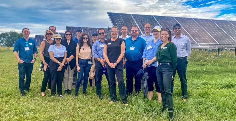 Energy execs in front PV arrays.