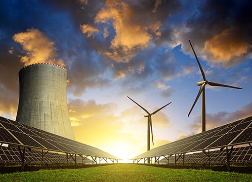 Nuclear power plant in front of solar arrays and wind turbines