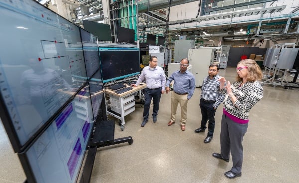 four people viewing data on video screens