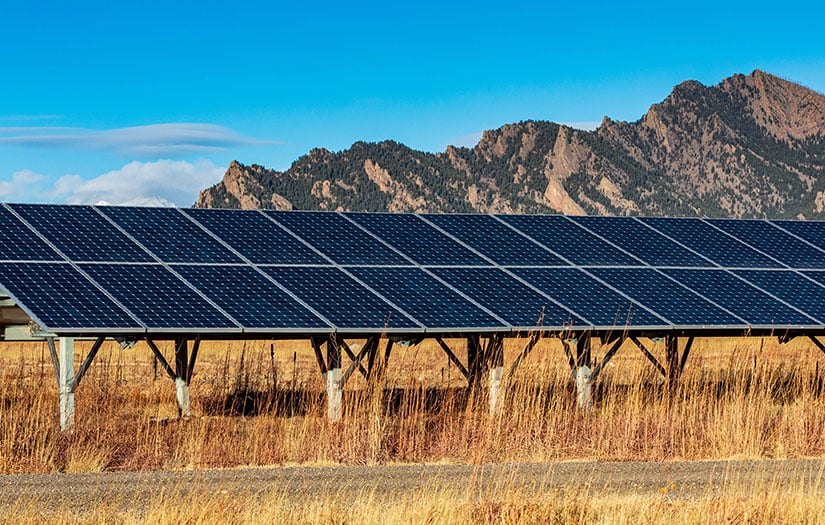 Solar PV arrays in a field with mountain range behind it