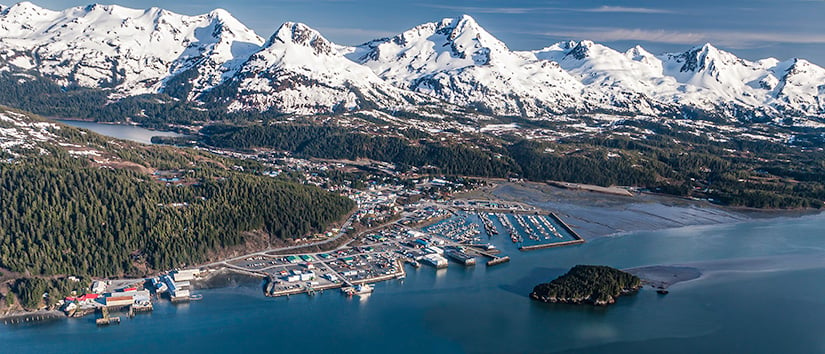 Aerial view of Cordova, Alaska shoreline with mountain range in background.