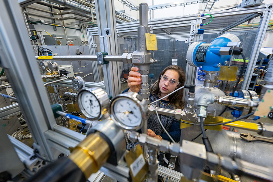 Electrical engineer works inside research facility testing high-power hydrogen electrolyzer stack test bed.