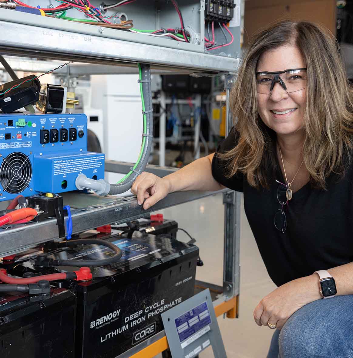 Person bends down to adjust equipment inside lab