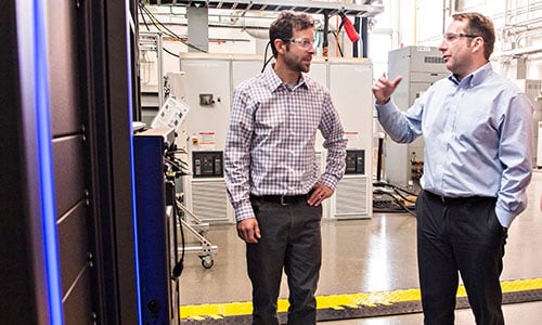 Two people in a lab look inside computer system.