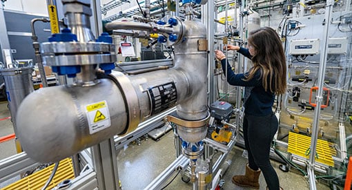 Person in safety glasses uses a tool to adjust pipes on lab equipment