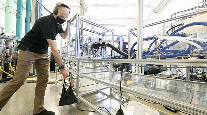 Person places sandbag on lab equipment inside facility.