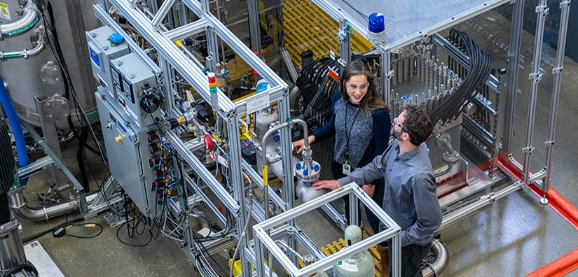 Two researchers looking at mechanical equipment in the ESIF.