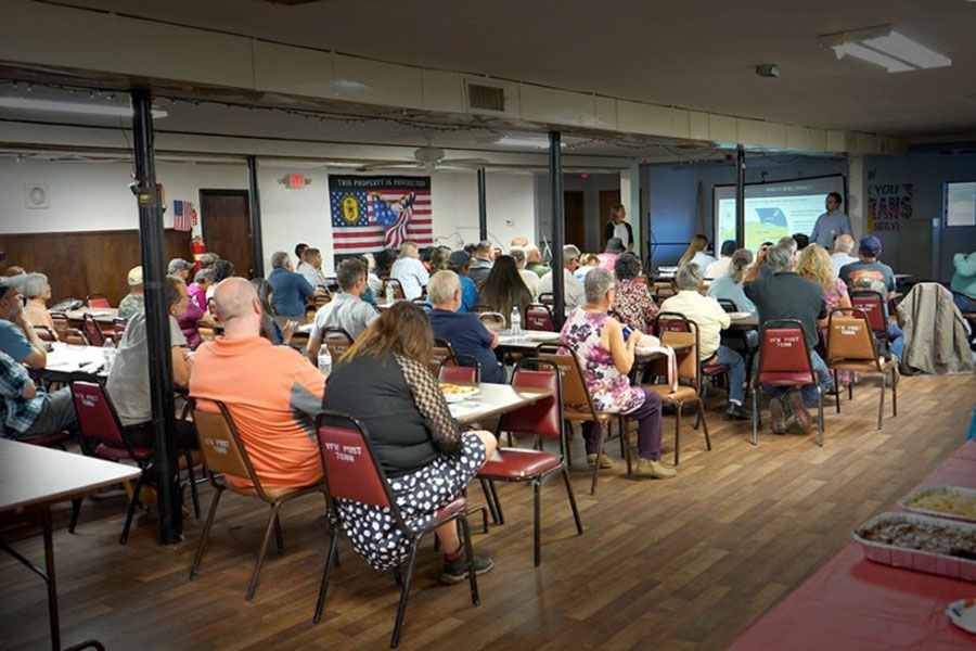 A photo of a group of people seated and facing forward toward presenters in an interior room.