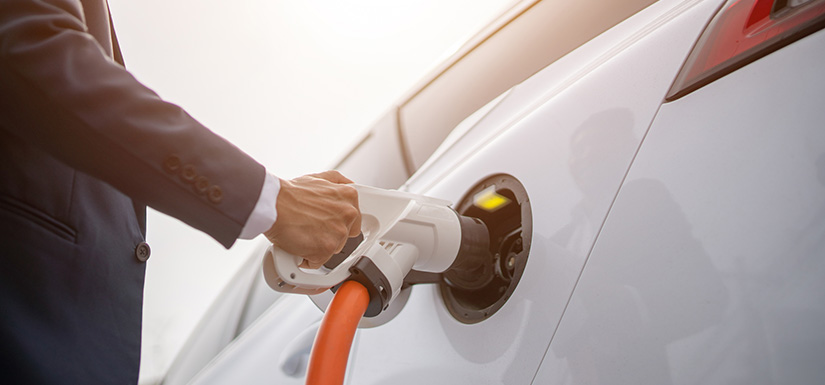 A hand holding a plugged in electric car charger.