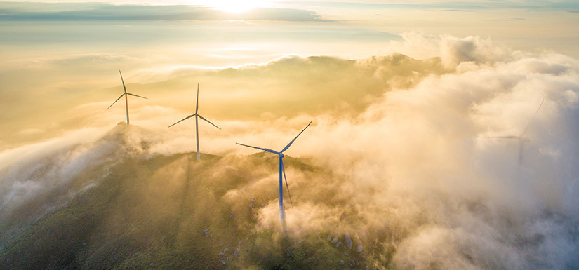 Wind turbines appearing above the clouds.