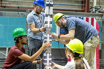 People work on a flexible wave energy converter device