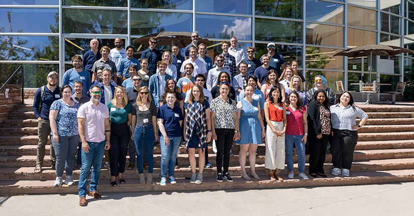 A large group of people standing on a staircase in front of an NREL facilities.