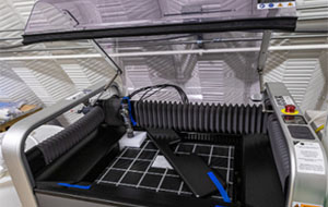 360tour-01-5602 A machine with transparent lid open, revealing a gridded platform interior.