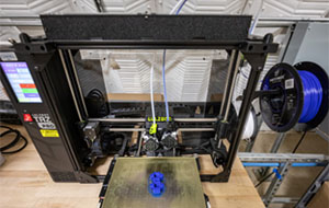 360tour-04-5558 A machine sits on a desk top with wires and sliding components exposed in the interior.