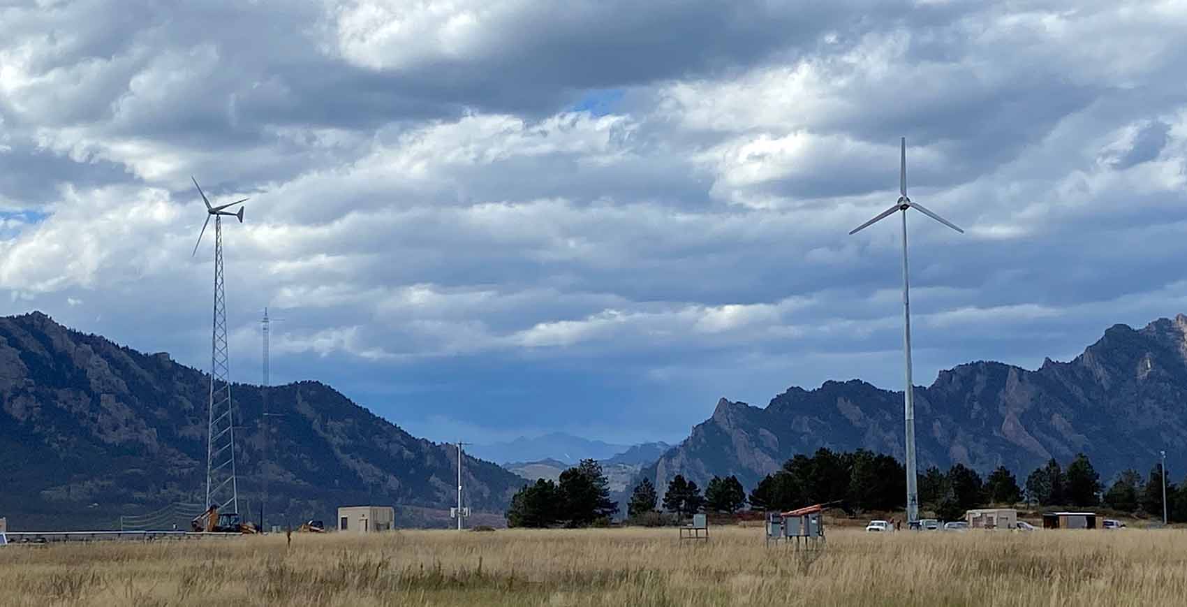 Three small wind turbines against a mountain backdrop.