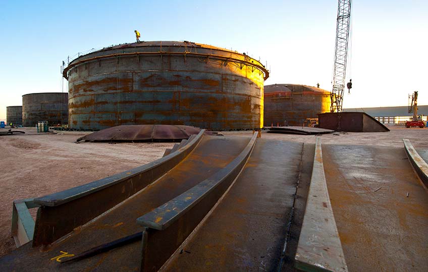 Sun sets on a group of large, circular tanks.