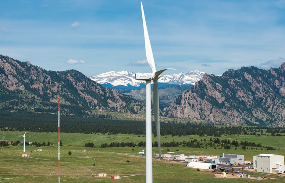 A wind turbine in a field with mountains in the background at NREL's National Wind Technology Center