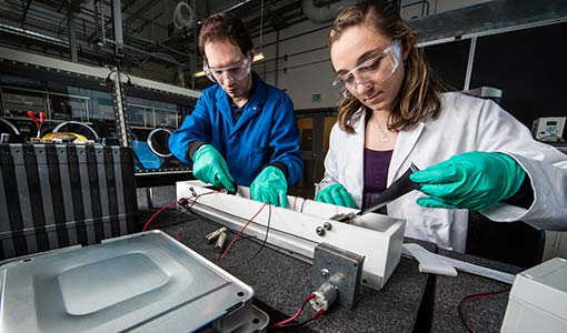 Researchers in laboratory setting working with technical components.