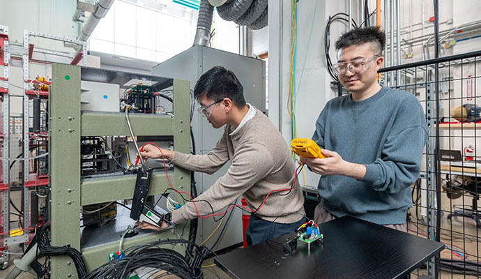 Two people work on electronics inside laboratory