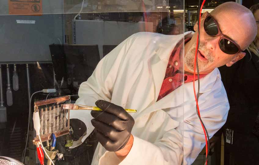 A man paints perovskites onto a piece of glass, creating a solar cell.