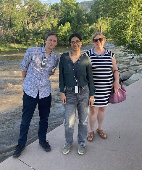 Three people in front of a river.