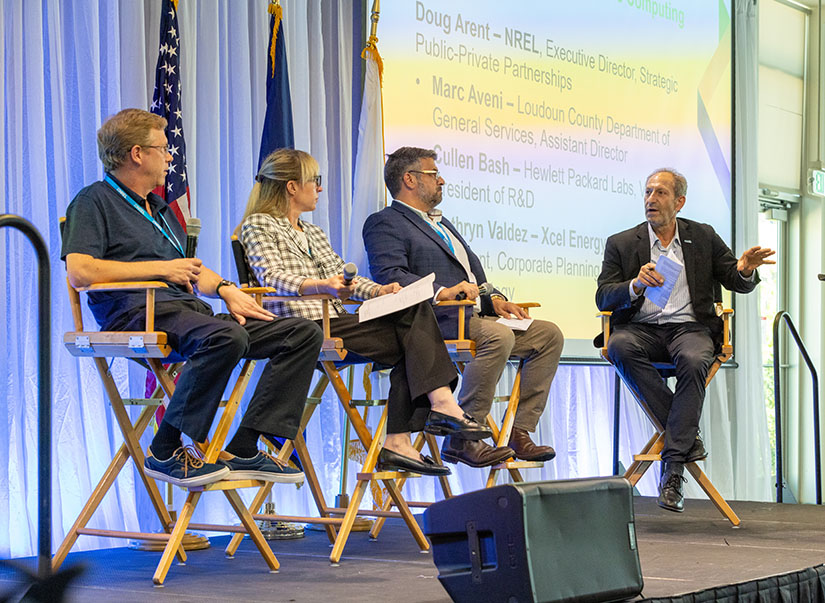 Three people seated on stage listen intently to a panel moderator. 