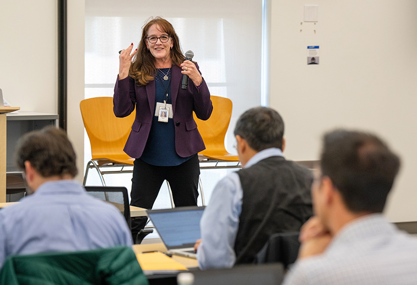 A researcher gives a presentation to a room full of people.