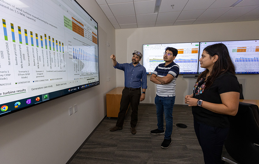 Three researchers looking at data on a large screen.