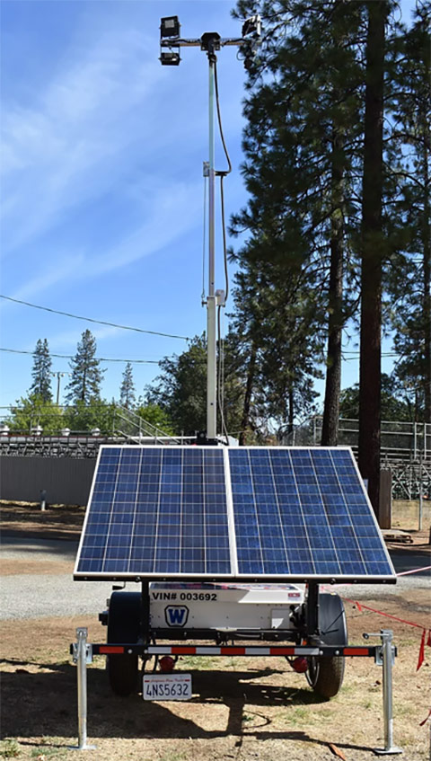 A solar-powered light tower in a forest