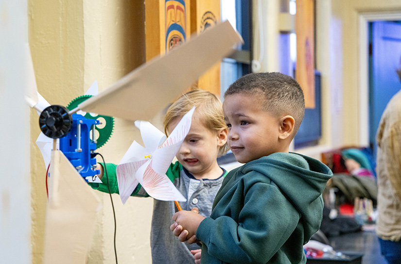 Two children hold up a craft project. 