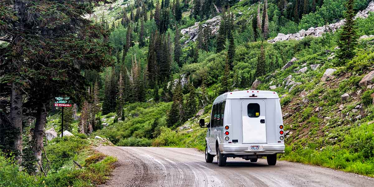 A shuttle bus on dirt road in summer in the Wasatch mountains of Utah