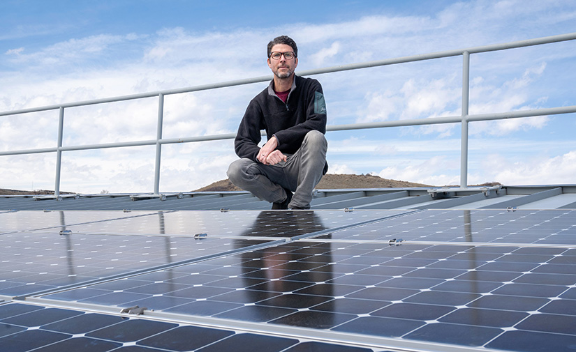 A man crouches near an array of solar panels.