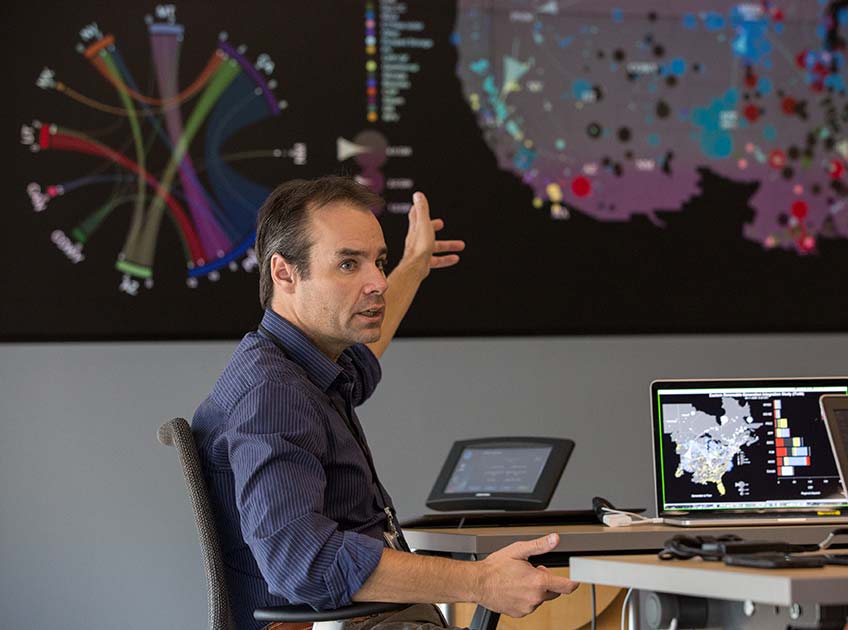 A man points to a projected data visualization of the U.S. power grid