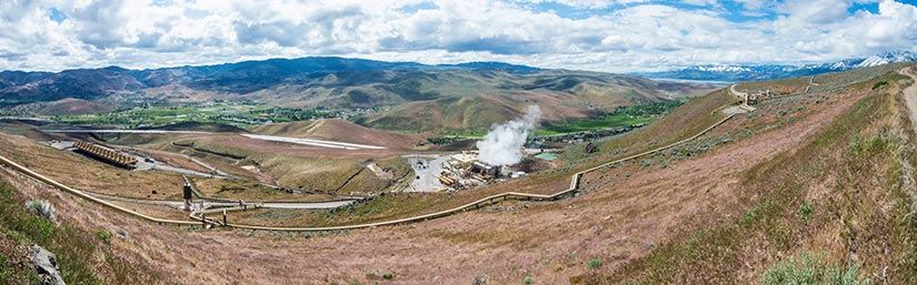 Steam coming off of a geothermal plant in a valley.