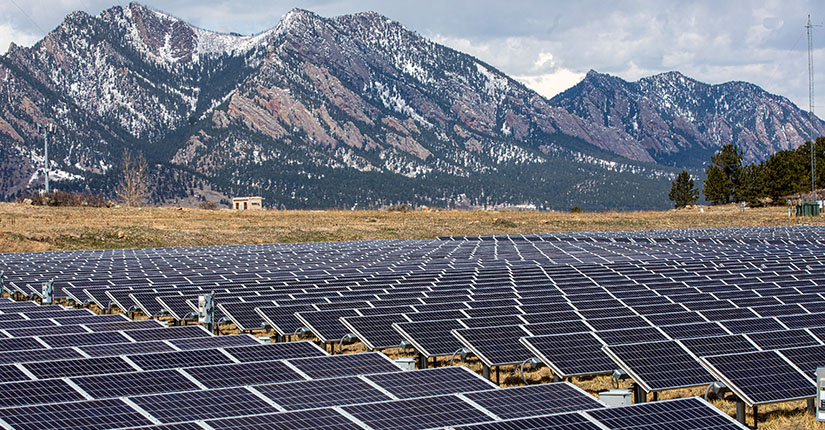 Rows of solar panels with mountains in the background.